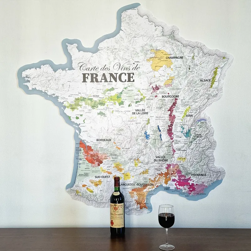 Carte des vins de France découpée au mur, avec une bouteille et un verre de vin rouge