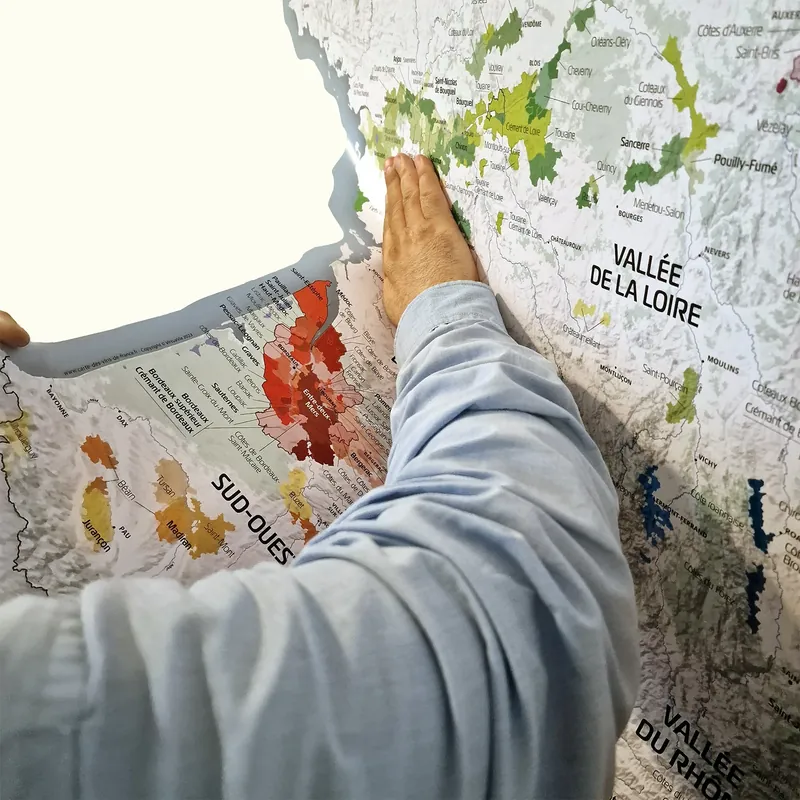 Main lissant le sticker mural carte des vins de France pendant la pose