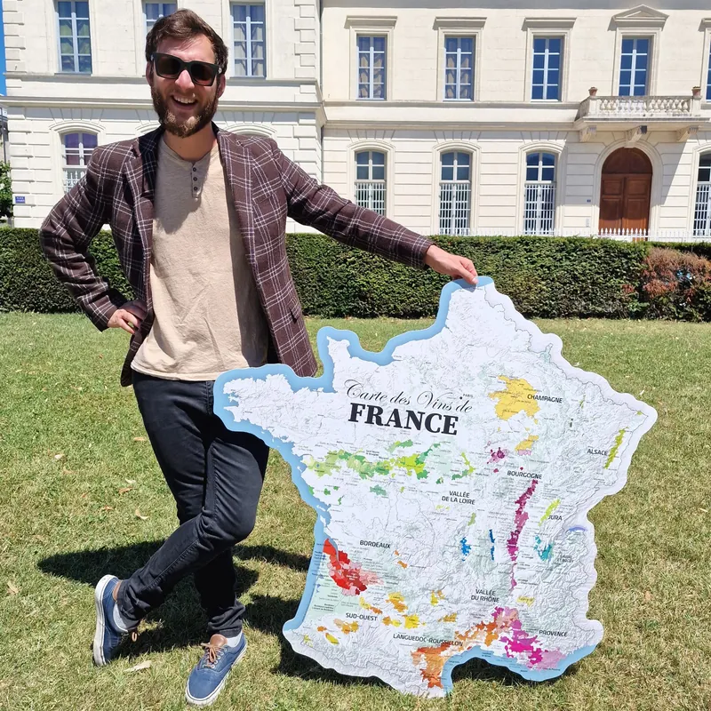 Homme tenant la carte des vins de France découpée de 120 cm devant un château